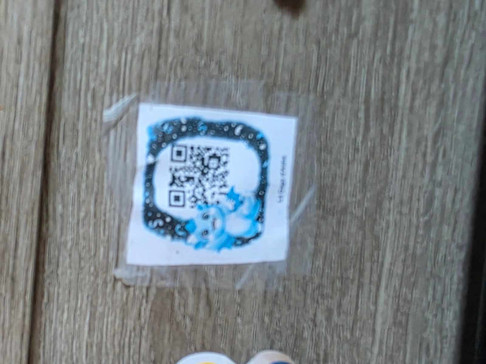 Le tout premier QR code de la première chasse au trésor : un carré plastifié, scotché sur une porte de meuble, avec un petit dragon bleu dessiné à la main autour du code, au milieu des autocollants d’enfant.