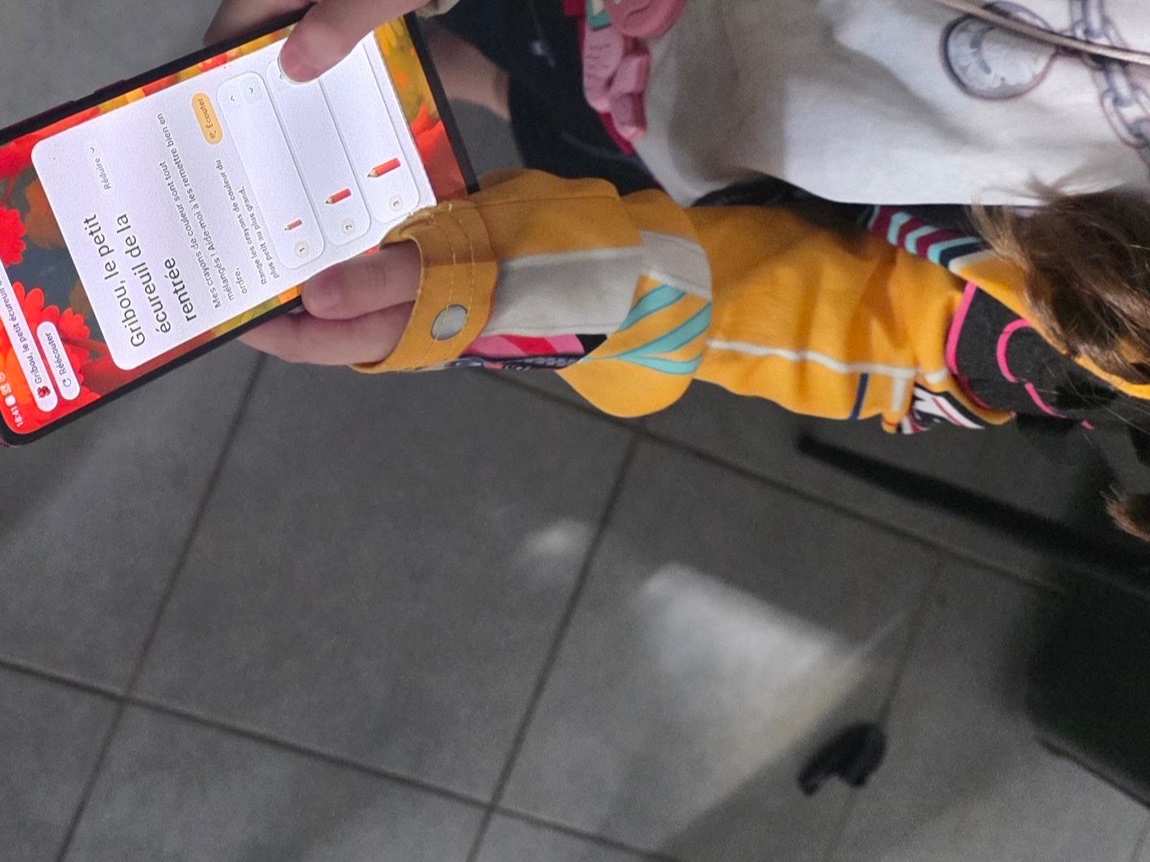 Une enfant tient le téléphone, qui raconte l’aventure de Gribou pendant qu’elle joue.